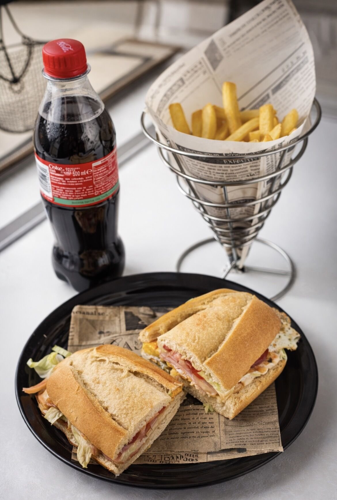 Combo: bocadillo abierto en dos mitades, cono de papas fritas y Coca-Cola